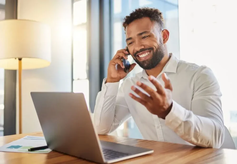 Guy talking on a phone looking at laptop